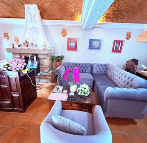 Una sala de estar con un sofá gris, una mesa de centro de madera y una chimenea de piedra.