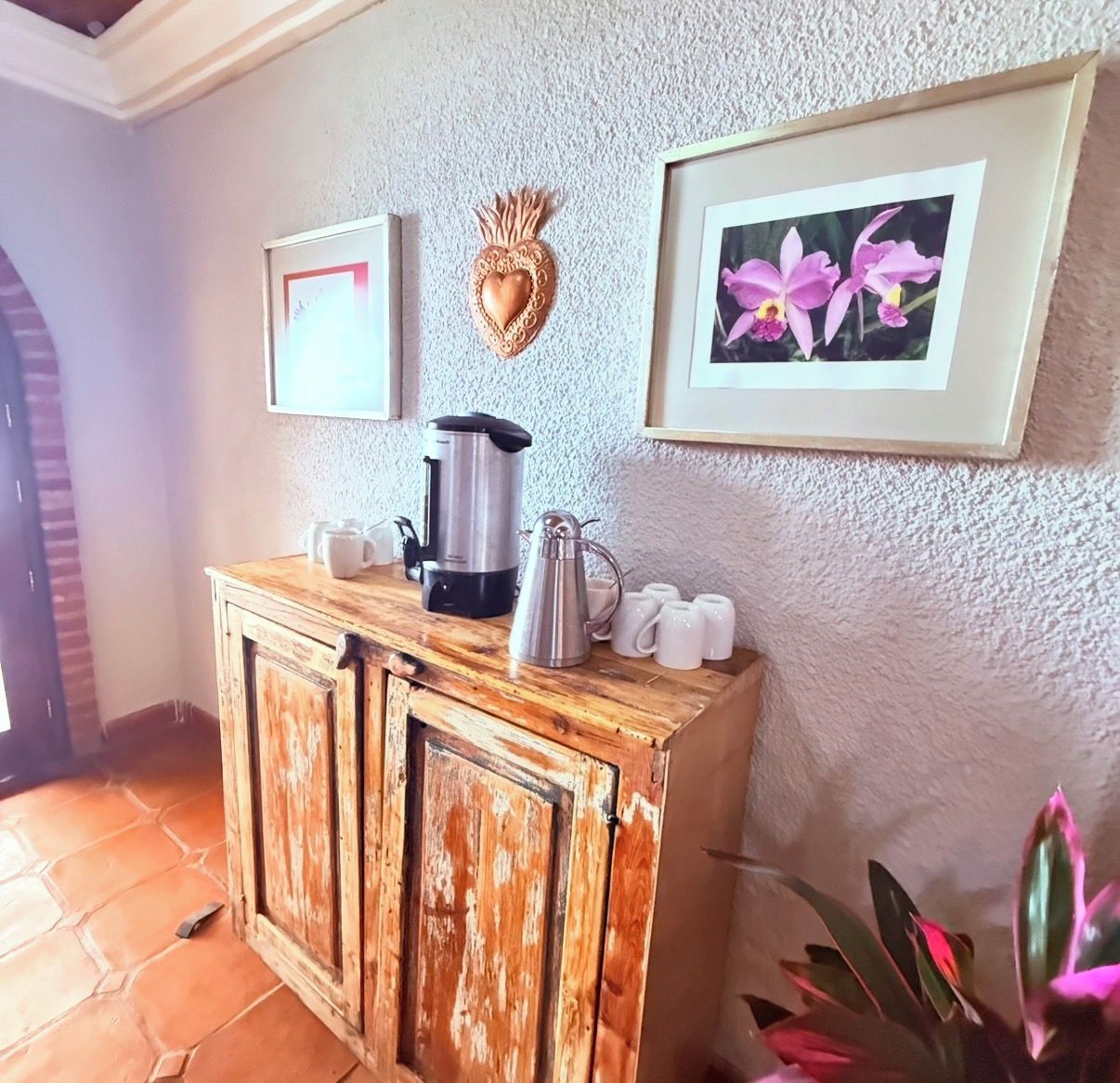 A kitchenette with a coffee maker, mugs, and a decorative heart on the wall.