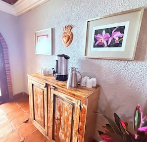 Una kitchenette con cafetera, tazas y un adorno con forma de corazón en la pared.