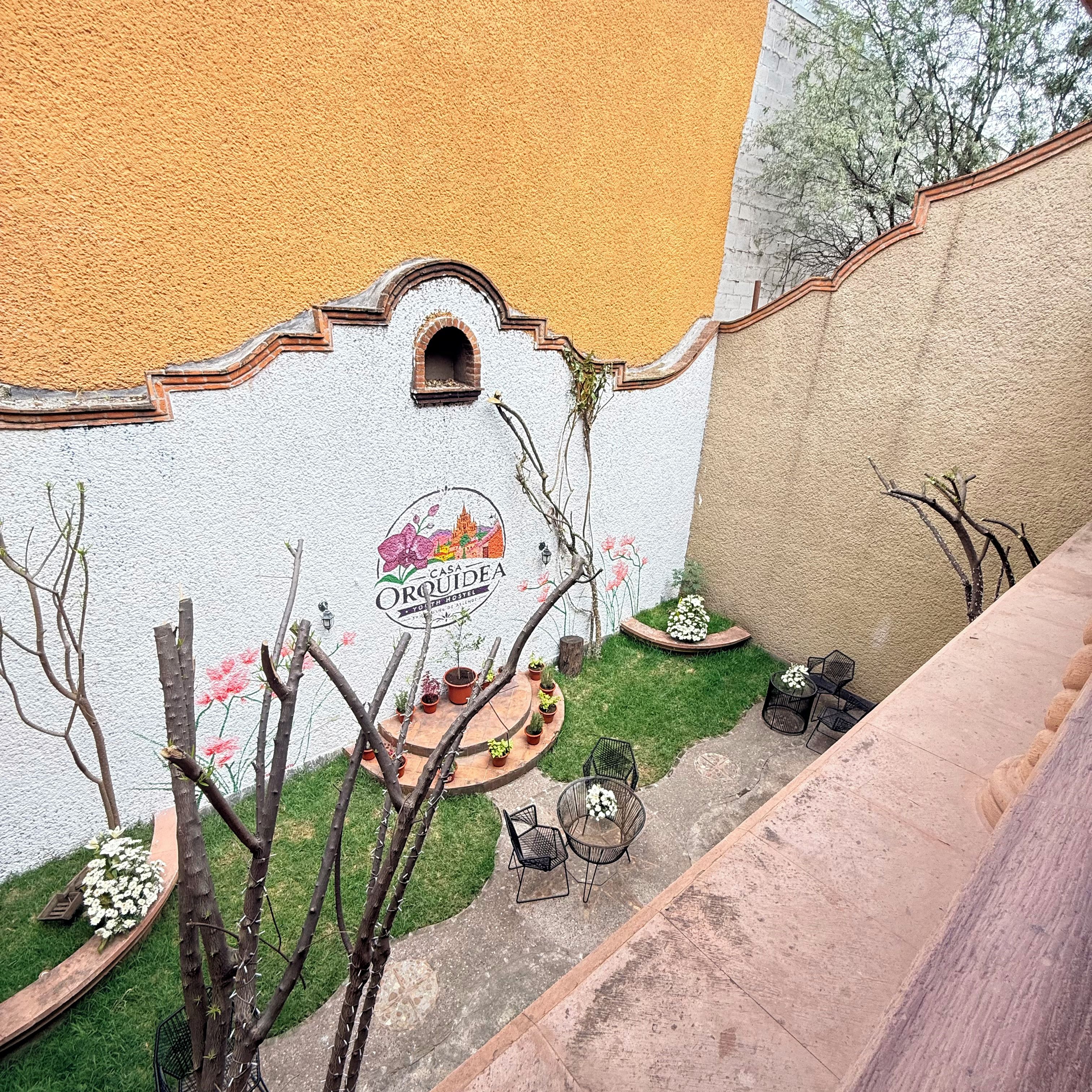 Un hostal con un mural, asientos exteriores y plantas en macetas.