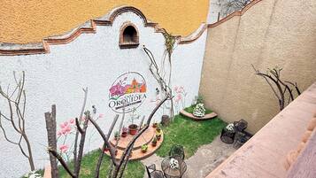 Un hostal con un mural, asientos exteriores y plantas en macetas.