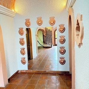 Un pasillo con apliques decorativos con forma de corazón y una escalera que conduce a un nivel superior.