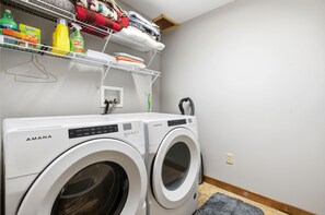 Eine Waschmaschine mit Frontlader, ein Bedienfeld, ein oberes Ablagefach mit Reinigungsmitteln und ein kleiner Spiegel an der Wand.