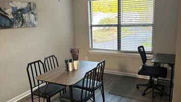 Un comedor con una mesa, sillas, ventilador de techo y una ventana con persianas.