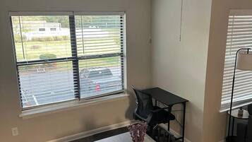 A dining area with a table, chairs, a ceiling fan, and windows with blinds.