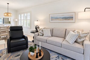 A living room with a sofa, a black armchair, a coffee table with candles, and a painting on the wall. - Lakefront Shorewalk Palms Condo Easy Does It (Bradenton)