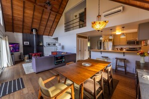 A modern kitchen with a central island, wooden dining table, and bar stools. - The Catskill Oasis · Private Pond, Creek, Trails, Hot Tub (Napanoch)