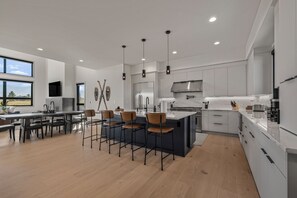 A modern kitchen with a central island, pendant lighting, and a view of the outdoors. - New Luxury 4 bed | Hot Tub w/ Teton View | Targhee | AC (Driggs)