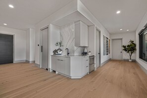 A modern kitchen with white cabinetry, a marble backsplash, and a built-in oven. - New Luxury 4 bed | Hot Tub w/ Teton View | Targhee | AC (Driggs)