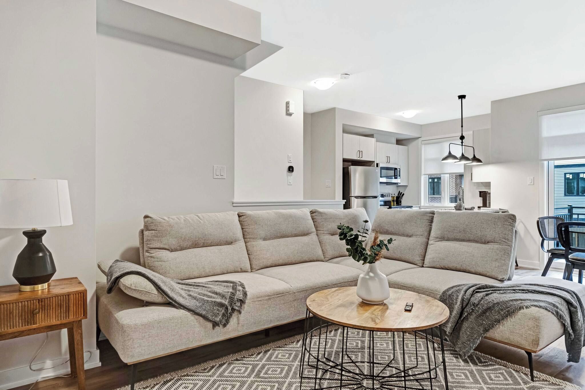 A modern living room with a sectional sofa, a round coffee table, and a side table with a lamp.