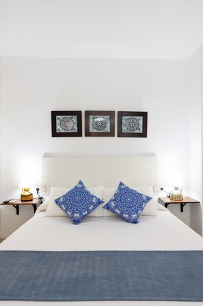 A hotel room with a large bed, two pillows, a nightstand with a lamp, and three framed wall art pieces. - Encanto Nazarí · Your Little Corner in Granada (Granada)