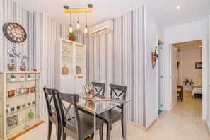 A dining area with a glass table and chairs, a clock on the wall, and a striped wallpaper design. - Encanto Nazarí · Your Little Corner in Granada (Granada)