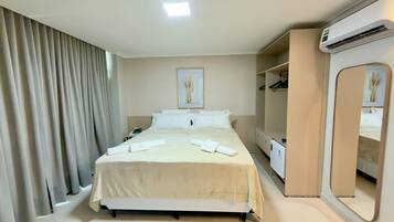 Una habitación de hotel con una cama, una mesita de noche, un espejo, un aire acondicionado y un armario.