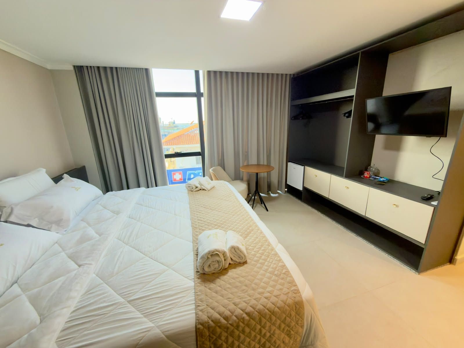 Una habitación de hotel con una cama, televisión, escritorio y una silla.
