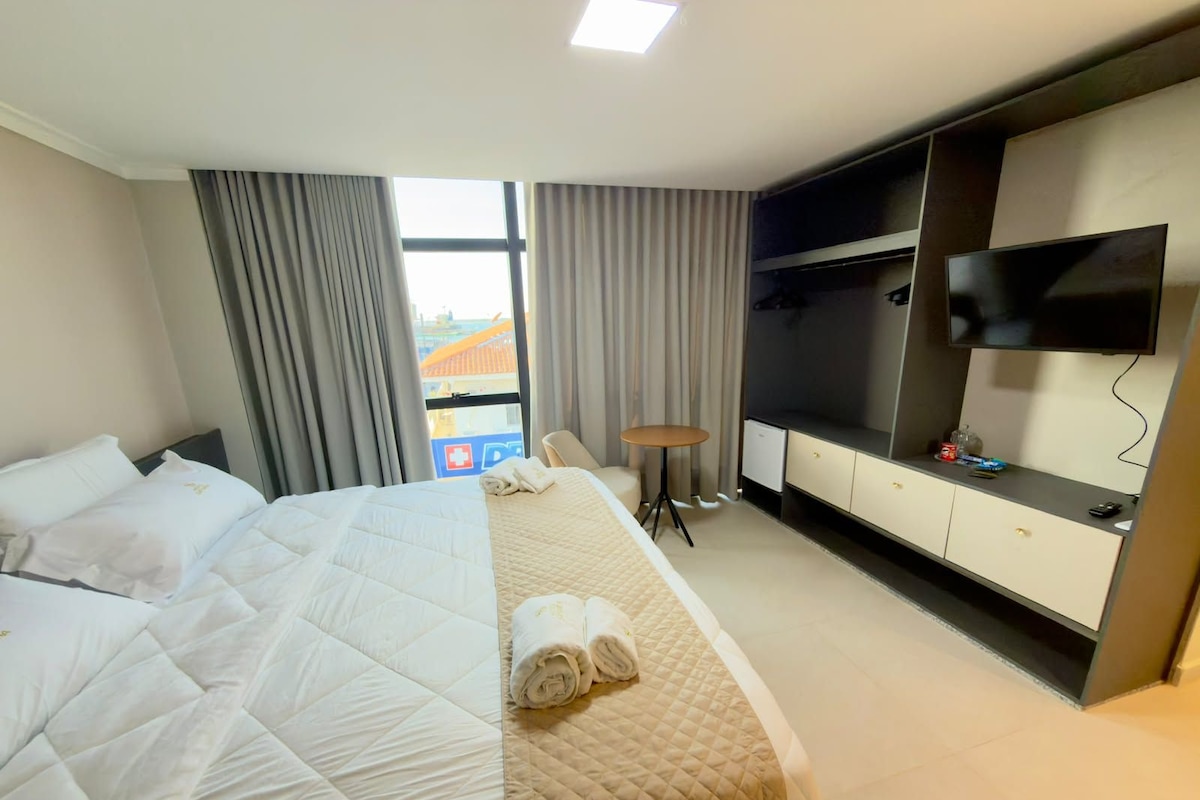 Una habitación de hotel con una cama, televisión, escritorio y una silla.