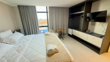 Una habitación de hotel con una cama, televisión, escritorio y una silla.