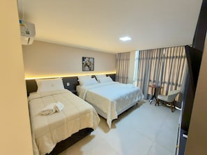 Habitación de hotel con dos camas, una mesita, una silla y un televisor.
