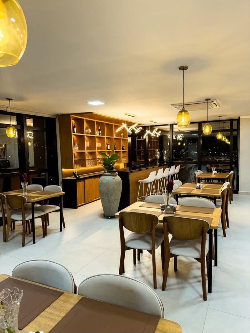 A modern dining area with multiple tables and chairs, a bar area with shelves, and a large vase.