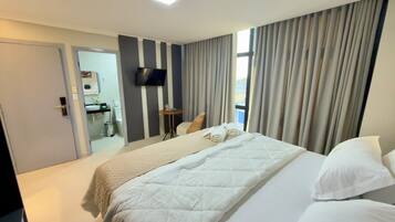 Ein Hotelzimmer mit Bett, Fernseher, einem kleinen Tisch und einem durchgegangenen Badezimmer.