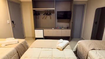 A hotel room with two beds, a TV, a wardrobe, and a small desk.
