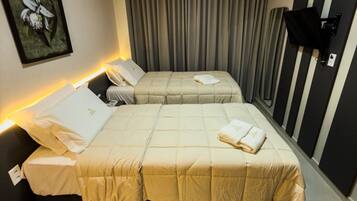 Habitación de hotel con dos camas, un cuadro en la pared y un televisor montado.