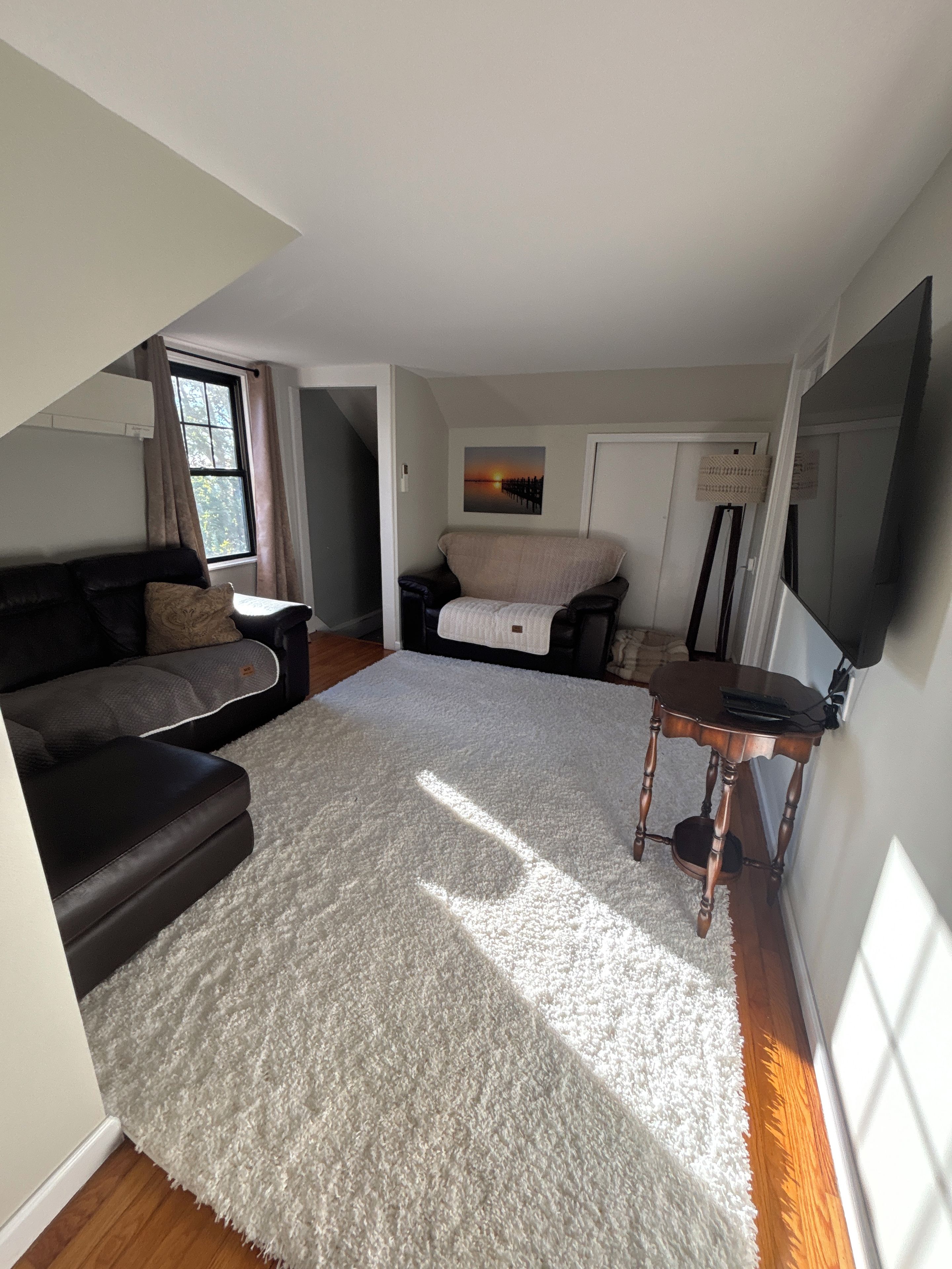 A compact living space with a sofa, a small table, a TV, and a painting on the wall.