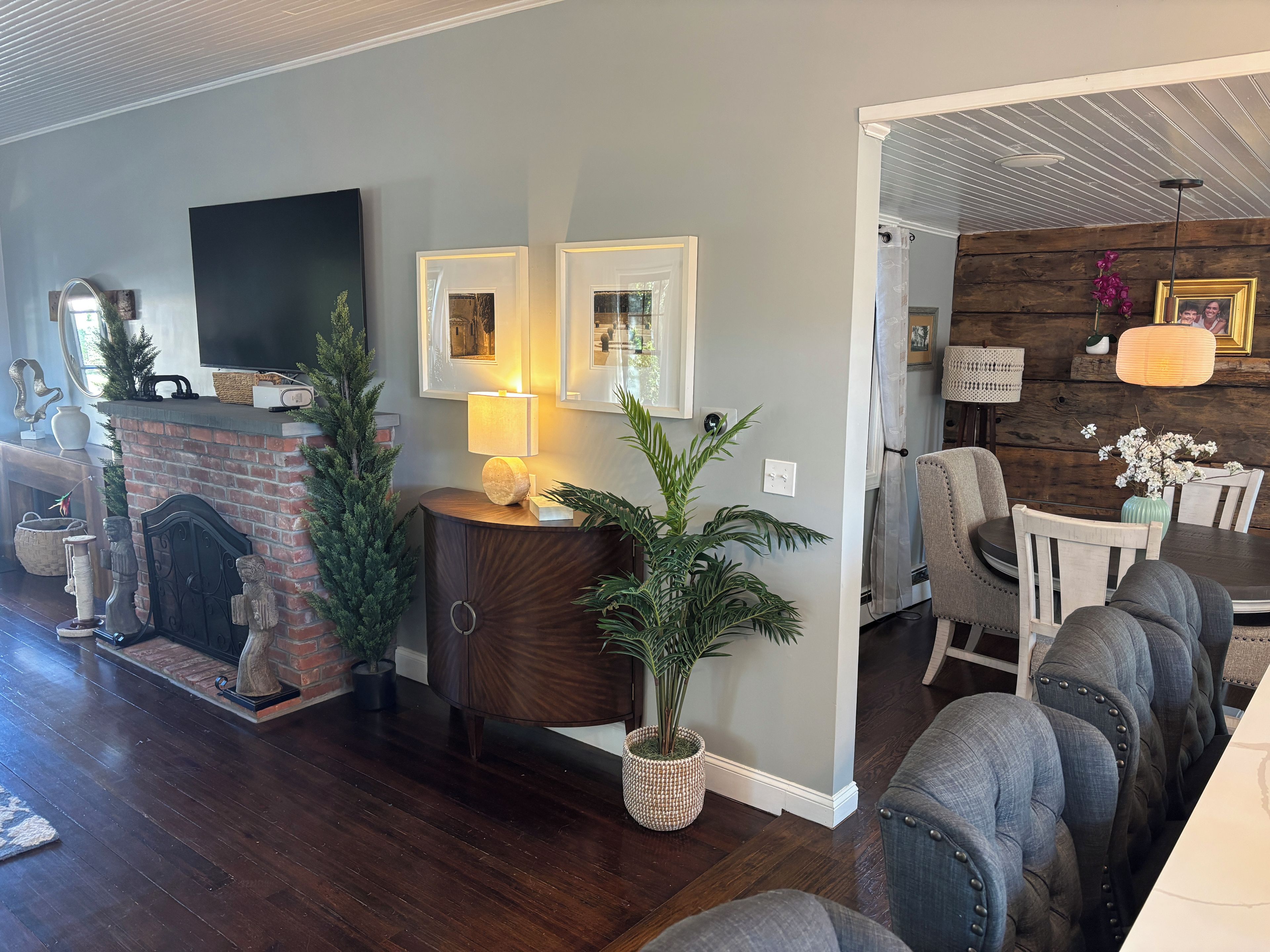 A modern living room with a fireplace, a flat-screen TV, and a dining area with a table and chairs.