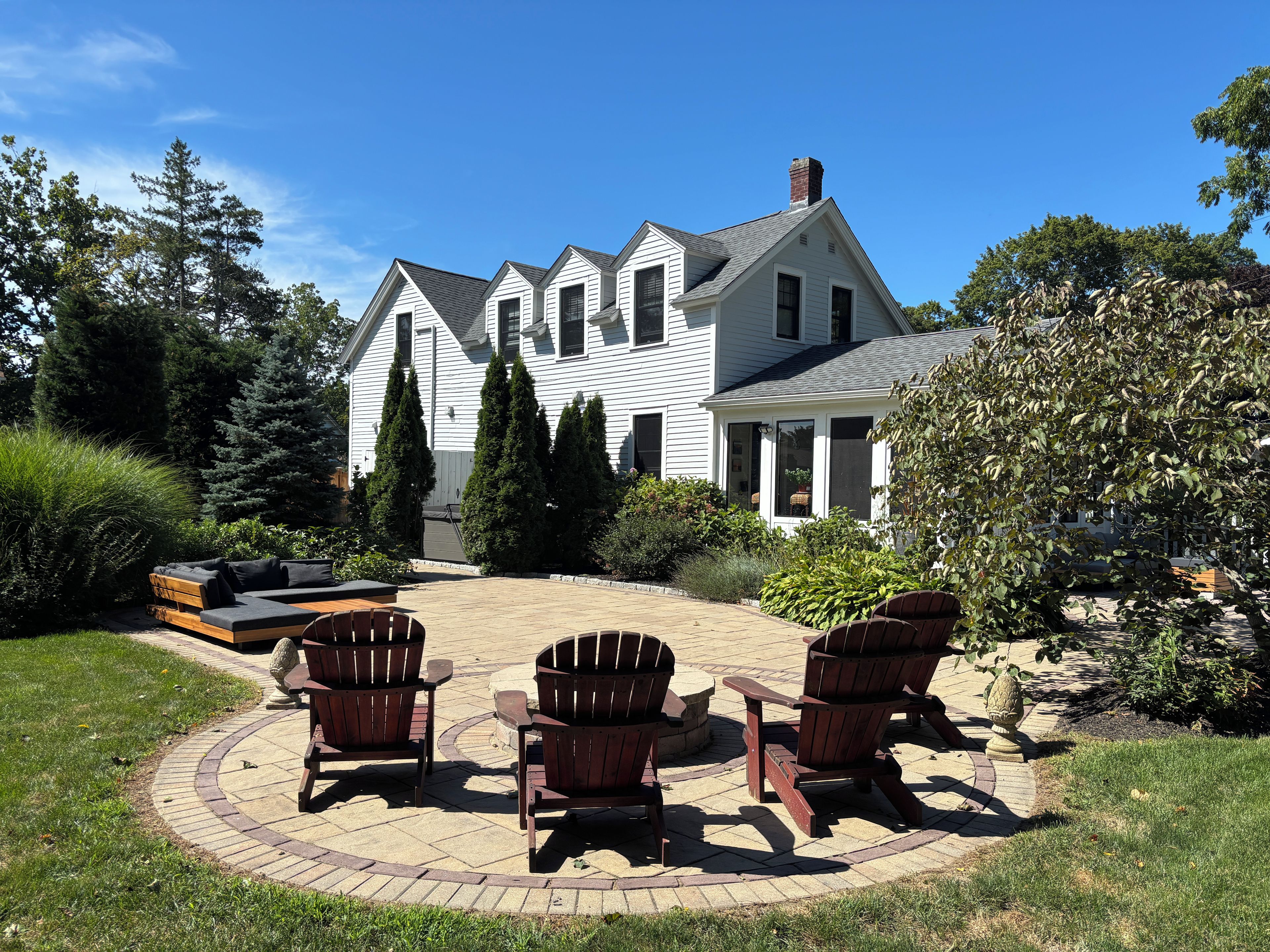 A house with a patio area featuring Adirondack chairs and a fire pit.