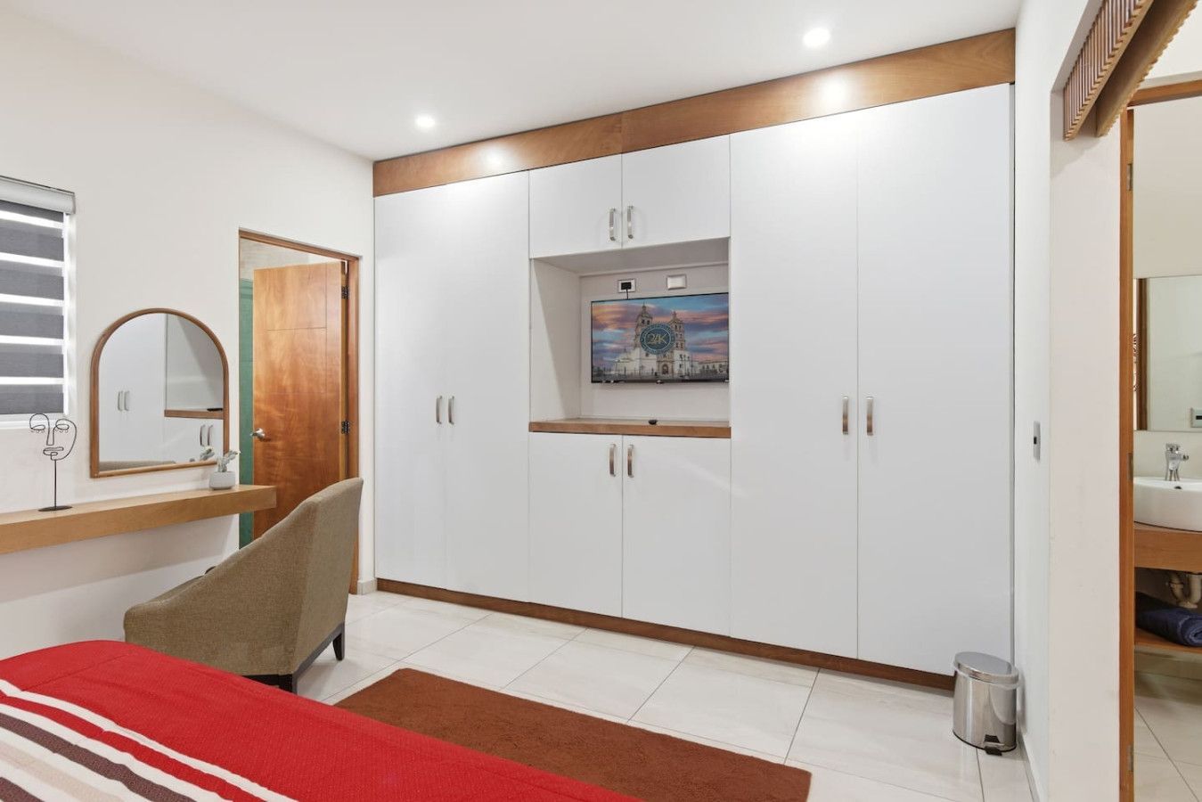 A bedroom with a bed, a wardrobe, a mirror, and a painting on the wall.
