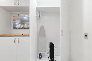Una stanza con un armadio bianco, una TV a schermo piatto fissata al muro e un surf illuminato appoggiato al muro.
