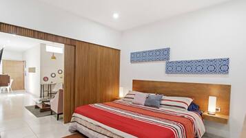 A modern bedroom with a large bed, a wooden headboard, and a bedside table with a lamp.