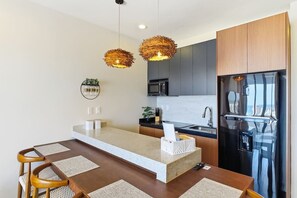 A modern kitchen with a central island, stainless steel appliances, and a dining area with wooden chairs. - Ocean & Old Town views | Rooftop pool (Mazatlán)