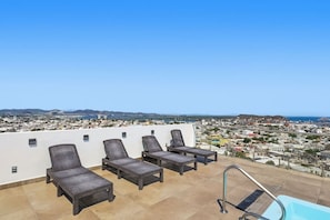 A rooftop terrace with four lounge chairs, a pool, and a city view. - Ocean & Old Town views | Rooftop pool (Mazatlán)