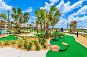 A miniature golf course with palm trees, a pool, and lounge areas. - 4BR Near Disney, Private Heated Pool, Storey Lake Resort, Sleeps 12 (Kissimmee)