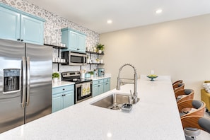 A modern kitchen with stainless steel appliances, light blue cabinets, and a white countertop. - 4BR Near Disney, Private Heated Pool, Storey Lake Resort, Sleeps 12 (Kissimmee)
