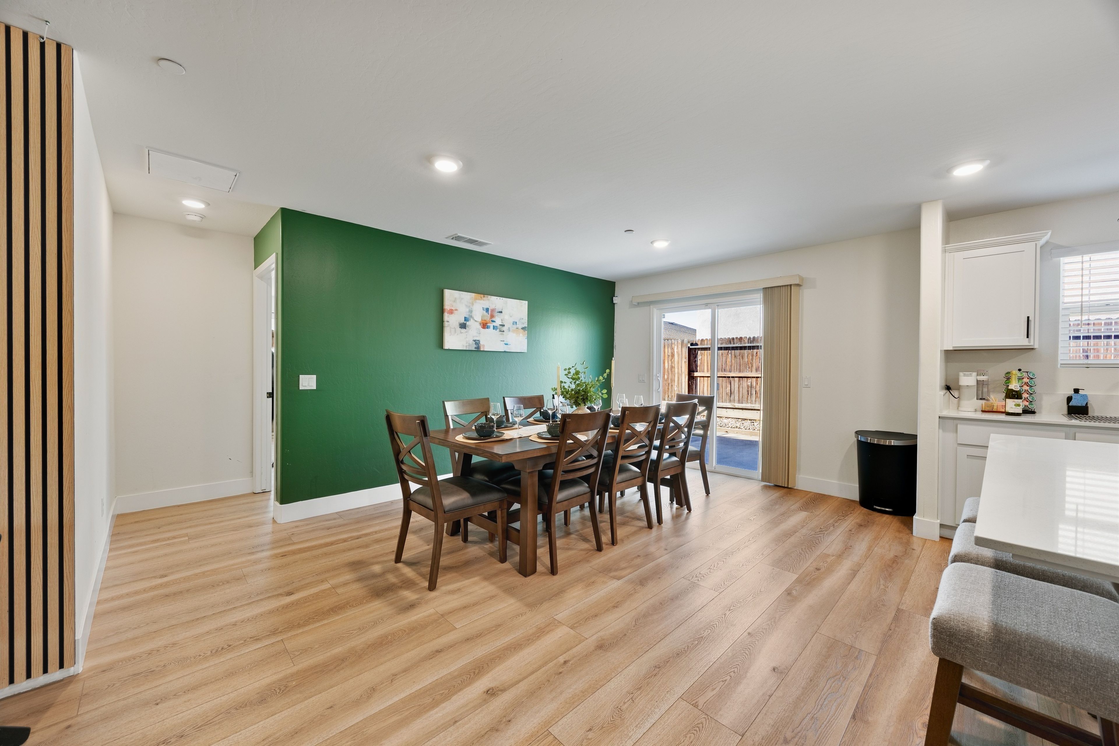 Comedor con pared verde, suelo de madera y una mesa preparada para cuatro comensales.