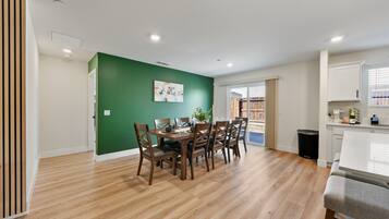 Comedor con pared verde, suelo de madera y una mesa preparada para cuatro comensales.