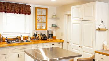 A kitchen with white cabinets, a stainless steel island, and two bar stools.