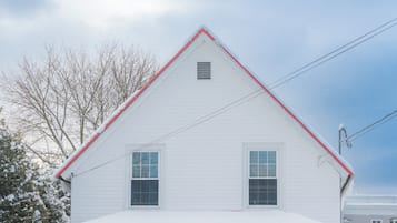 A white house with a red roof, a porch with a bench, and a door with a wreath.