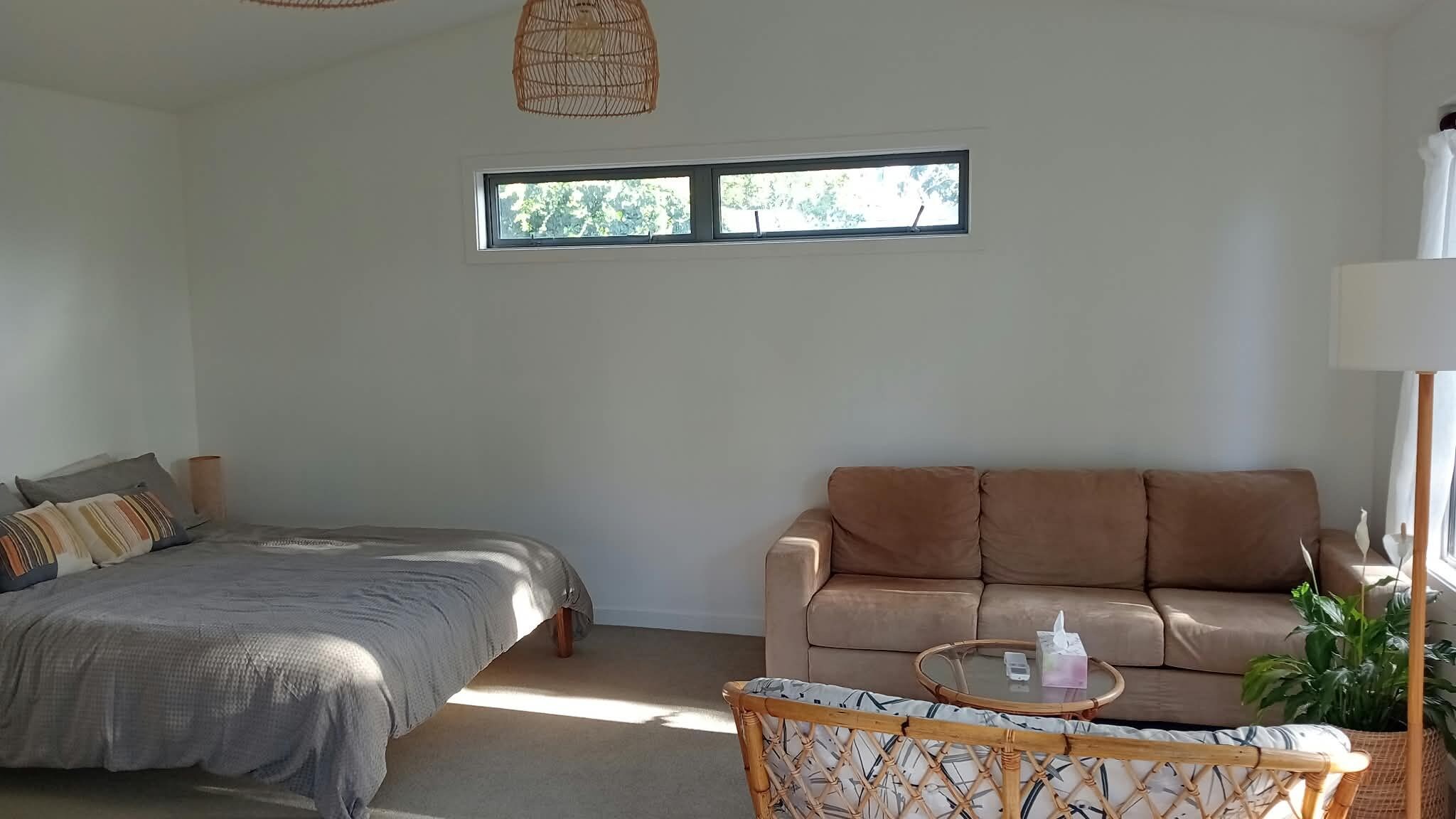 A bedroom with a bed, a sofa, a round coffee table, and a window.