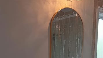 Ein Badezimmer mit einer weißen Toilette, einem runden Waschbecken mit einem hölzernen Waschtisch und einem großen Spiegel über dem Waschbecken.