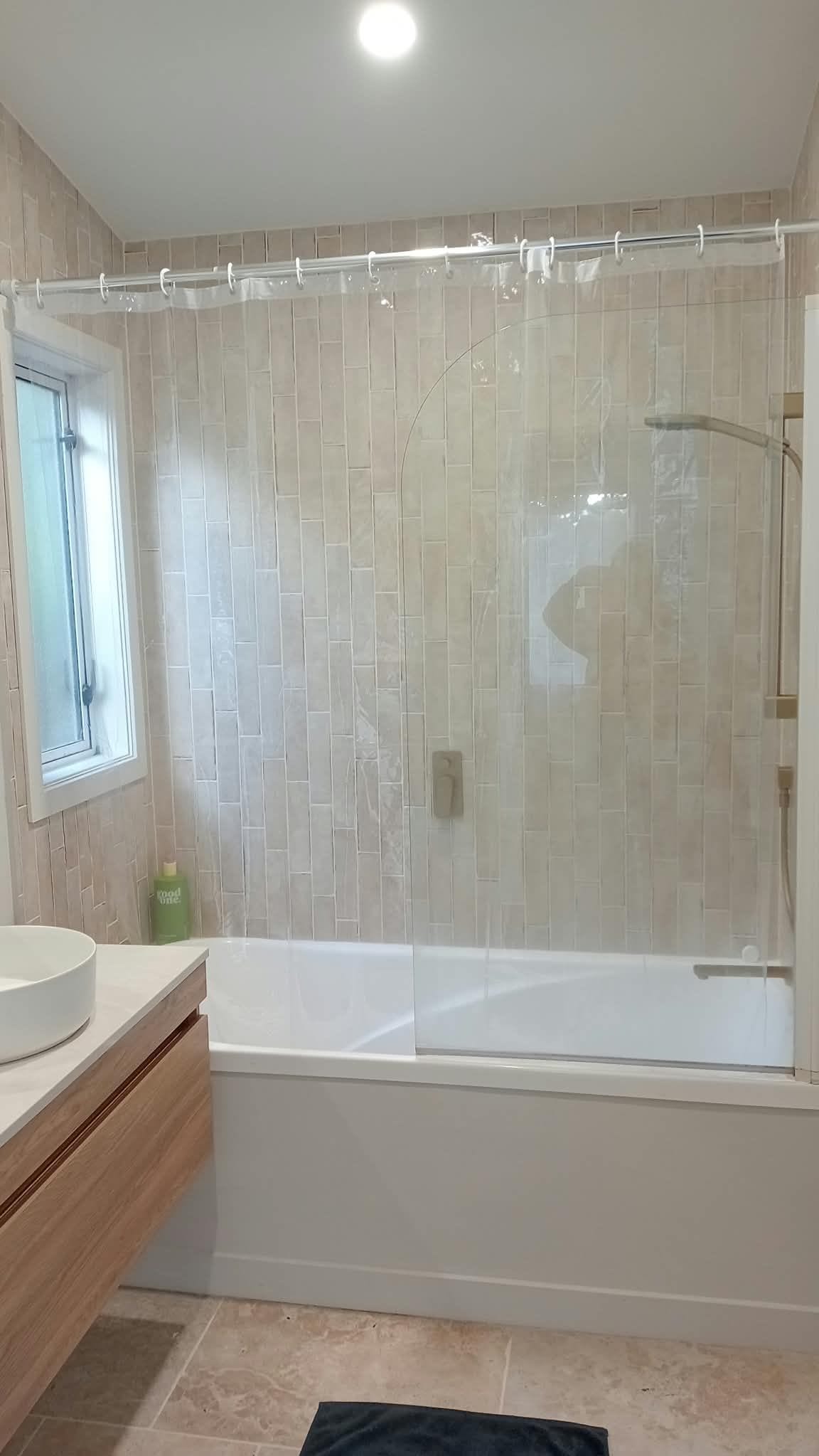 A bathroom with a bathtub, a shower, and a vanity with a mirror.
