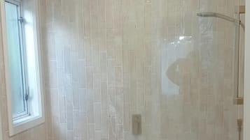 A bathroom with a bathtub, a shower, and a vanity with a mirror.