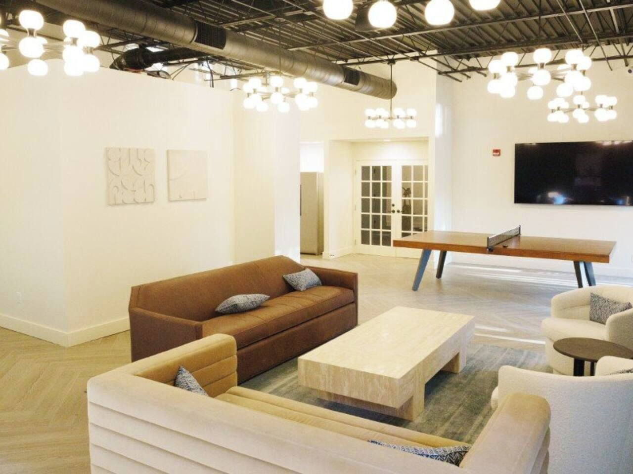 A modern interior with a brown sofa, white armchairs, and a wooden coffee table.