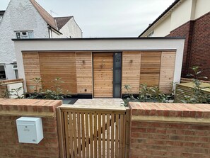 Ein modernes Gebäude mit Holzfassade, einem Metallgitter und einer Ziegelwand.