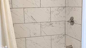 Une salle de bain avec une baignoire blanche, des toilettes et un espace douche séparé par un rideau.