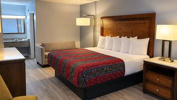 Une chambre d’hôtel comprenant un lit, des tables de chevet, une chaise, un bureau et un miroir.