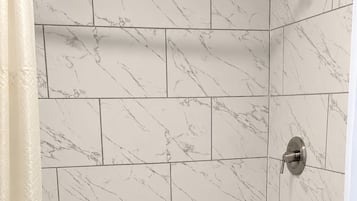 Une salle de bain avec une baignoire, des toilettes et des murs recouverts de carreaux de marbre.