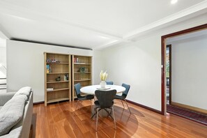 Ein Zimmer mit einem runden Tisch, zwei Stühlen, einem Bücherregal und einem Sofa.