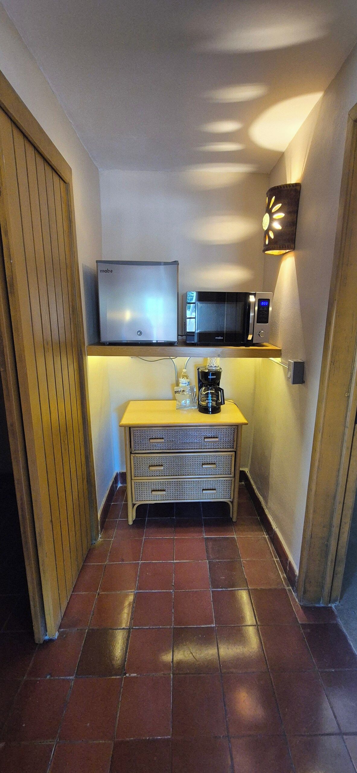 Cocina compacta equipada con refrigerador, microondas, cafetera y una pequeña encimera.